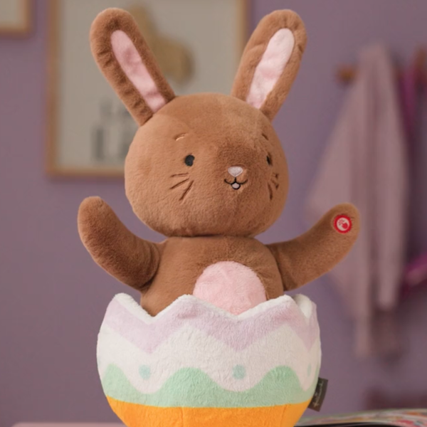 An interactive plush in the form of a light brown Easter Bunny popping out of a pastel-colored Easter egg; the plush features sound and motion and will be available at Gold Crown stores and at Hallmark.com this Easter 2026.